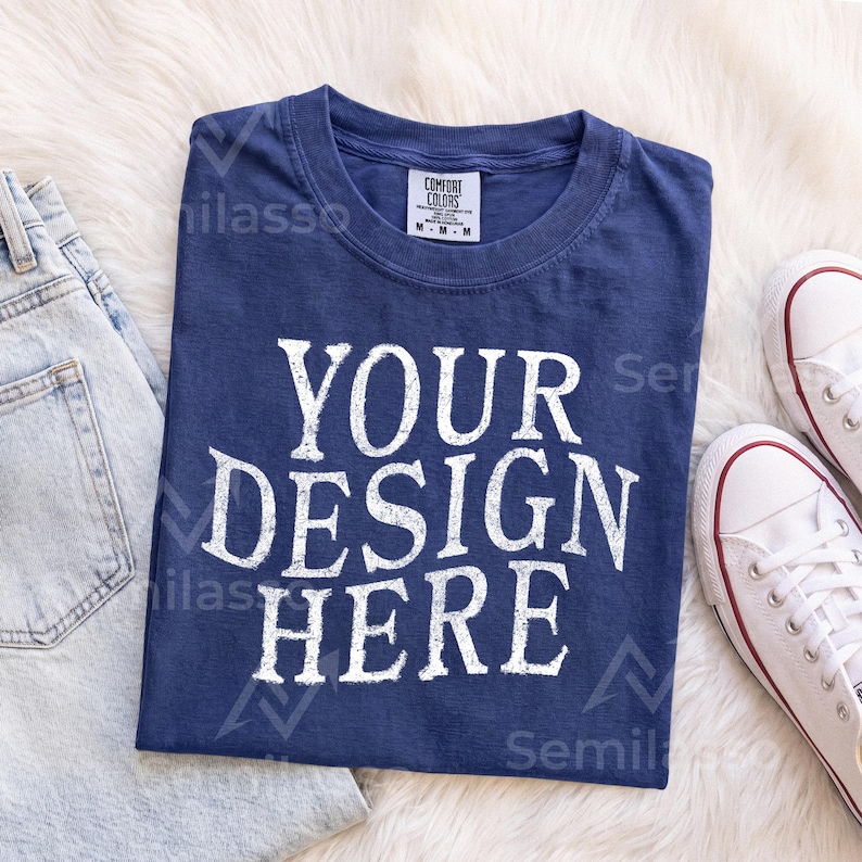 May include: A navy blue short-sleeve t-shirt with a crew neckline and a white distressed-style graphic print that reads "YOUR DESIGN HERE" in large capital letters. The shirt features a white interior neck label with the text "COMFORT COLORS".