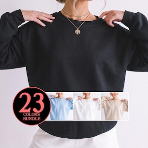 May include: A solid black long-sleeve crewneck sweatshirt. A circular graphic in the bottom left corner displays the text 23 COLORS BUNDLE in pink and black. Smaller inset images show the same sweatshirt in light blue, white, and beige.