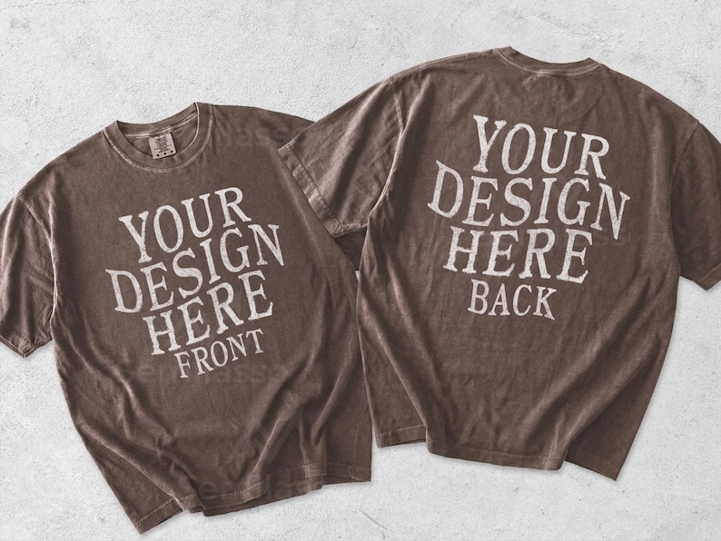 May include: Two brown short-sleeve t-shirts with a distressed texture. The left shirt features white text reading YOUR DESIGN HERE FRONT. The right shirt features white text reading YOUR DESIGN HERE BACK. Both shirts have a crew neckline.