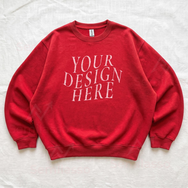 Puede incluir: Una sudadera roja de cuello redondo con mangas largas y pu&ntilde;os acanalados. En el centro del pecho aparece el texto blanco "YOUR DESIGN HERE" en una tipograf&iacute;a serif desgastada. La prenda incluye una etiqueta interior en el cuello.