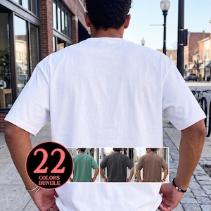 Può includere: Una t-shirt bianca a maniche corte vista da dietro. Un grafico circolare nell'angolo in basso a sinistra mostra il testo 22 COLORS BUNDLE e include tre piccole immagini che mostrano la stessa t-shirt in verde salvia, antracite e beige.