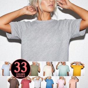 Puede incluir: Una camiseta gris claro con cuello redondo. La imagen muestra una variedad de camisetas en diferentes colores, con el texto "33 COLORS BUNDLE" en un diseño circular. Las camisetas se muestran en un modelo.