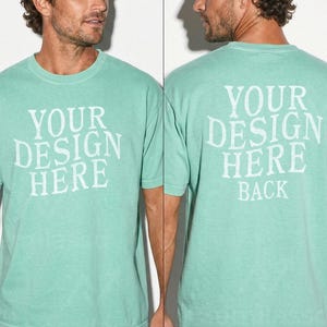 May include: A seafoam green t-shirt with the text "YOUR DESIGN HERE" on the front and "YOUR DESIGN HERE BACK" on the back. The shirt is short-sleeved and has a crew neck.