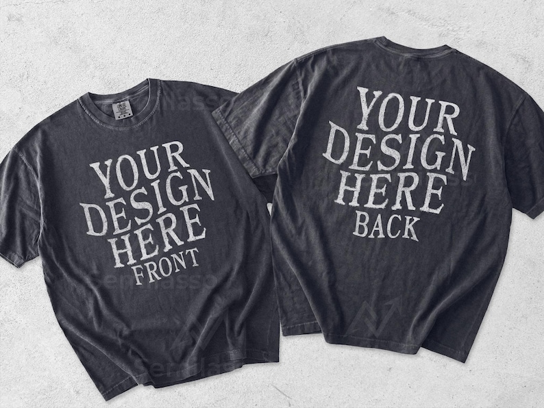 May include: Two charcoal gray short-sleeve t-shirts displayed side by side. The left shirt features the white text YOUR DESIGN HERE FRONT. The right shirt features the white text YOUR DESIGN HERE BACK. Both shirts have a crew neckline and a faded finish.