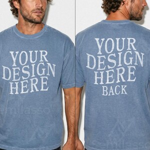 May include: A blue short-sleeved t-shirt with the text "YOUR DESIGN HERE" printed on the front and back. The back of the shirt also has the word "BACK" printed below the main text. The shirt has a vintage, faded look.