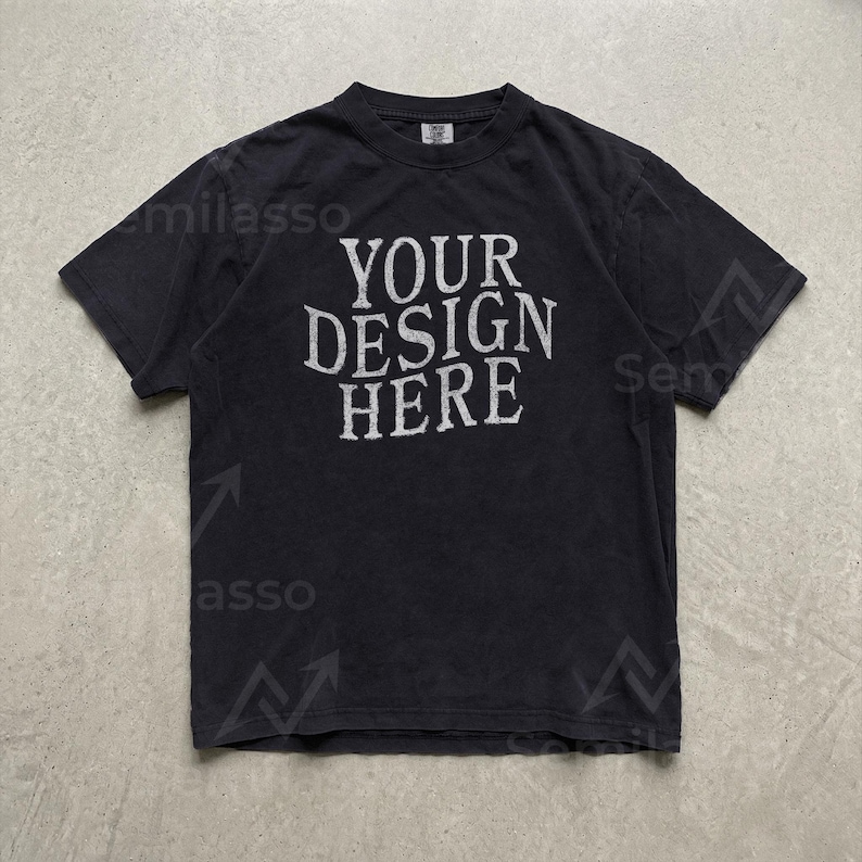 May include: A black short-sleeve t-shirt featuring the white text "YOUR DESIGN HERE" printed in a distressed, serif font across the center of the chest. The garment has a crew neckline and a standard fit, presented in a flat, front-facing view.