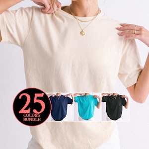May include: A short-sleeved crew neck t-shirt in a solid beige color. A circular graphic overlay in the bottom left corner displays the text 25 COLORS BUNDLE and shows three additional t-shirts in navy blue, bright turquoise, and black colors.