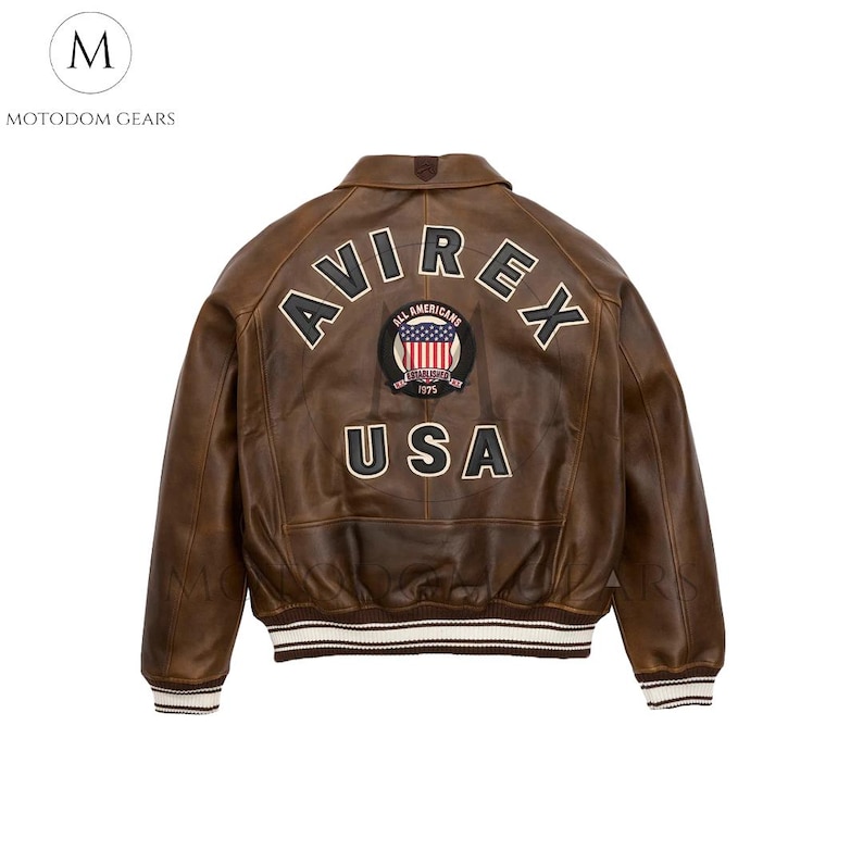 May include: Brown leather jacket with the word "AVIREX" arched across the back, above a patch with the American flag and the word "USA". The jacket has a collar and ribbed cuffs and hem.