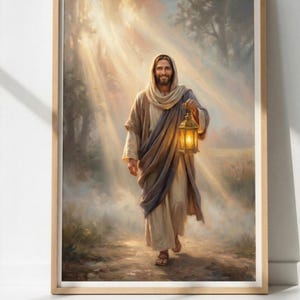 Può includere: Stampa incorniciata raffigurante una figura in abito, con in mano una lanterna accesa, che cammina lungo un sentiero. L'opera d'arte utilizza toni caldi, con la luce che filtra attraverso gli alberi. La figura ha un'espressione serena e il tema generale è spirituale.