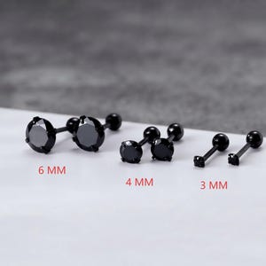 May include: Three pairs of black stud earrings with round faceted stones and ball backings. The pairs are labelled with text indicating sizes of 6 MM, 4 MM, and 3 MM. Each earring features a prong setting holding a dark stone on a thin metal post.