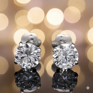 Puede incluir: Un par de pendientes de diamantes brillantes. Cada pendiente presenta un diamante grande de talla redonda engastado en una montura de plata o platino. Los pendientes se muestran sobre un fondo borroso de luz cálida y dorada.