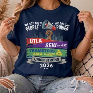 以下が含まれることがあります： 「WE GOT THE PEOPLE」と「WE GOT THE POWER」の文字が入ったネイビーブルーのTシャツ。メガホンのグラフィックと「UTLA」、「SEIU Local 99」、「TEAMSTERS AALA Local 2010」、「UNION STRONG 2026」の文字がデザインされています。