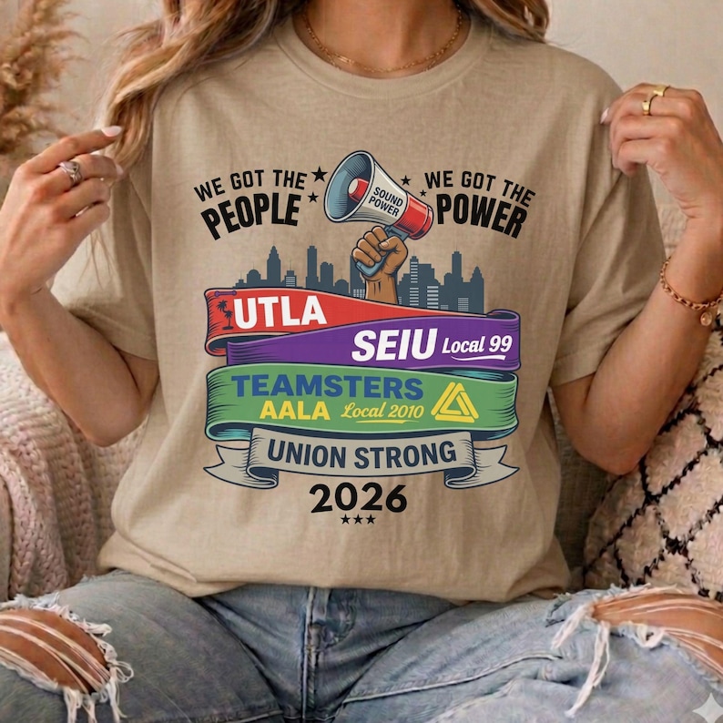 以下が含まれることがあります： 「WE GOT THE PEOPLE WE GOT THE POWER」の文字が入ったベージュ色のTシャツ。メガホンのグラフィックと「UTLA」、「SEIU Local 99」、「TEAMSTERS AALA Local 2010」、「UNION STRONG 2026」の文字が特徴です。