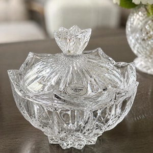 Puede incluir: Un cuenco para dulces de cristal de plomo transparente con tapa a juego, con un diseño facetado en forma de estrella y un remate puntiagudo. Una pegatina circular en la parte frontal dice Full Lead Crystal Gorham Germany.