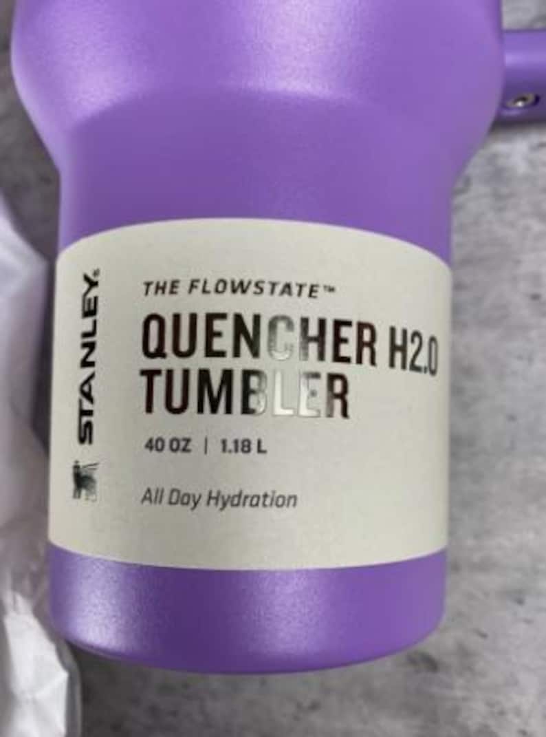 Op de afbeelding: Een paarse Stanley Quencher H2.0 Tumbler. De beker heeft een inhoud van 1,18 liter en is voorzien van de tekst "All Day Hydration". De beker is ontworpen voor hydratatie onderweg.
