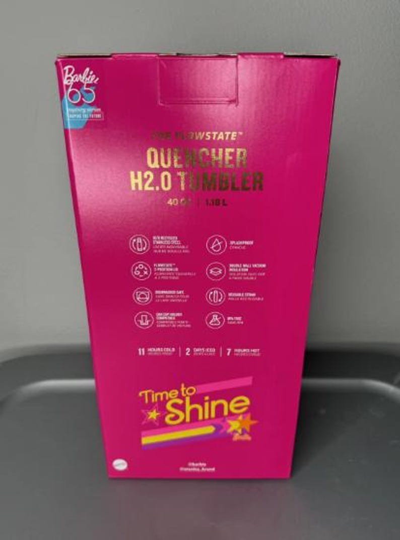 K&ouml;nnte beinhalten: Eine leuchtend pinke Box f&uuml;r einen "QUENCHER H2.0 TUMBLER". Die Box hat goldfarbene Schrift und Symbole, mit dem Text "Time to Shine" und "Barbie 65". Der Becher fasst 1,18 L und h&auml;lt Getr&auml;nke 11 Stunden kalt.