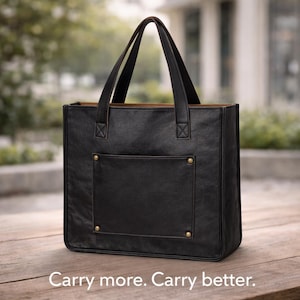May include: Black leather tote bag with a rectangular front pocket and gold-colored rivets. The bag has two handles and a brown interior. The text "Carry more. Carry better." is at the bottom of the image.