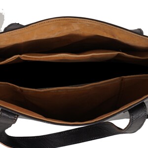 May include: Open view of a black leather tote bag with a light brown interior. The bag has multiple compartments and a structured design. The handles are also black leather. The bag appears to be empty.
