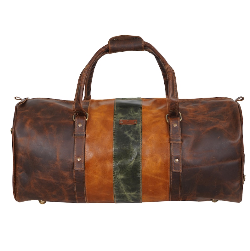 Pu&ograve; includere: Una borsa da viaggio in pelle marrone con finitura invecchiata. La borsa presenta una striscia verticale centrale verde oliva, affiancata da sezioni in pelle marrone chiaro e marrone scuro. Ha un manico superiore e due manici laterali.