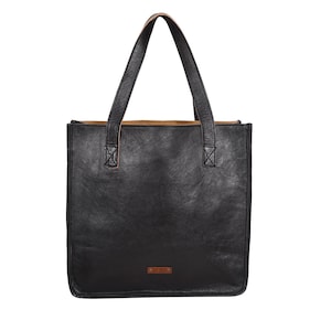 May include: A black leather tote bag with two long handles. The bag has a rectangular shape with a small brown tag on the front. The handles are attached to the bag with reinforced stitching. The interior of the bag is a lighter brown color.