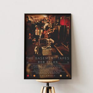 May include: A framed poster featuring a vintage photograph of a band playing instruments in a dimly lit room. The poster is titled "The Basement Tapes" by Bob Dylan, with a list of song titles and the Columbia Records logo.