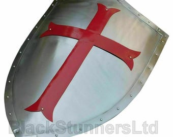 May include: A medieval shield with a polished metal finish. It features a large, vibrant red cross against the metallic surface. The edges are reinforced with metal and rivets. A historical item.