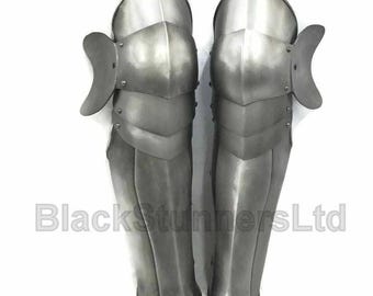 May include: Pair of silver-colored metal leg armor, likely for historical reenactment or display. The armor is segmented, with articulated plates for flexibility. The text "BlackstunnersLtd" is visible.