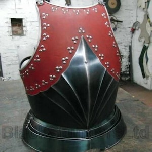 May include: A breastplate in the style of medieval armour, featuring a red leather upper section and a polished steel lower section. The red section is decorated with silver rivets. The breastplate has a curved design, suitable for historical reenactment or display.