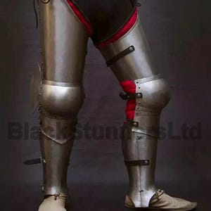 May include: A pair of steel leg armor, featuring articulated plates for knee protection and lower leg coverage. The armor has a polished finish with leather straps and rivets. The interior padding is red. The text "BlackStunnersLtd" is visible.