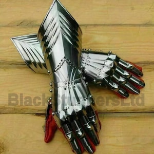 May include: A pair of polished steel gauntlets with articulated fingers and red leather lining. The gauntlets are designed with overlapping plates and rivets, reflecting light. The image is set against a wooden background.