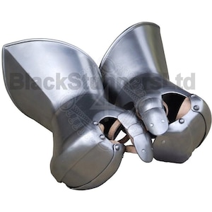 Op de afbeelding: Een paar zilverkleurige, gelede handschoenen, waarschijnlijk voor historische re-enactment of tentoonstellingen. De metalen handschoenen hebben een gepolijste afwerking en zijn ontworpen om de handen te beschermen. De handschoenen zijn gemaakt van meerdere platen, die aan elkaar zijn geklonken.