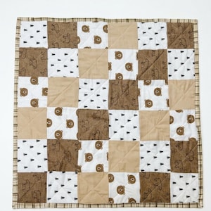 May include: A patchwork quilt featuring alternating squares of brown bear and tree patterns, solid tan, and white fabric. The quilt is bordered with a brown plaid fabric. The text "Made By Summer Studio" is at the bottom.