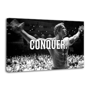 Puede incluir: Impresión en lienzo en blanco y negro que muestra a un hombre musculoso con los brazos levantados y la palabra "CONQUER" en letras blancas. El fondo muestra una multitud, creando un tema motivacional.