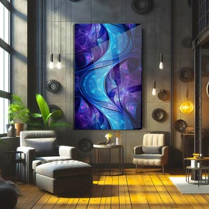 May include: Abstract art print in shades of blue and purple, displayed in a modern living room setting. The artwork features flowing, organic shapes. The room includes a grey armchair, ottoman, and wooden flooring.
