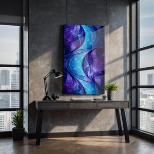 May include: Abstract art print in shades of blue and purple, mounted on a wall above a dark grey desk. A black desk lamp and a small potted plant are also visible. The room has large windows with a city view.