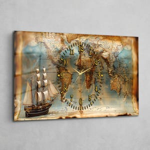 Op de afbeelding: Een rechthoekige wandklok met een vintage wereldkaartontwerp. De wijzerplaat is geïntegreerd in de kaart, met goudkleurige cijfers en wijzers. Een gedetailleerde illustratie van een zeilschip bevindt zich aan de linkerkant, wat het nautische thema versterkt.