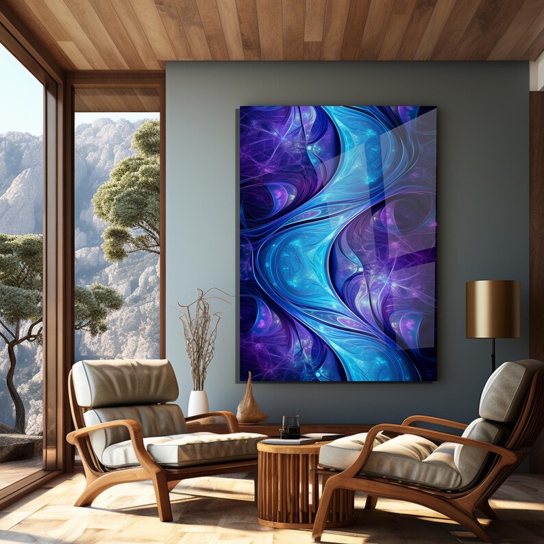 May include: An abstract artwork in shades of blue and purple, displayed in a modern living room. The room features wooden furniture, a small table, and a large window offering a view of a mountain landscape. The artwork is the focal point.