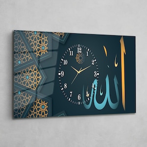 Può includere: Un orologio da parete rettangolare con sfondo blu scuro. Il quadrante è nero con lancette dorate e numeri arabi. Il design include motivi geometrici dorati e calligrafia araba in blu e oro.
