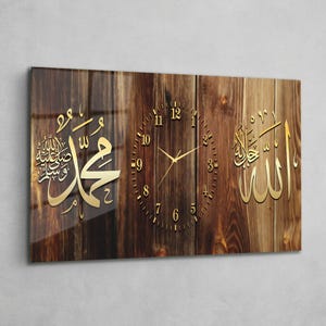 May include: A rectangular wall clock with a wooden effect background. The clock features gold Arabic calligraphy on the left and right, with a gold clock face in the centre. The clock hands and numerals are gold.