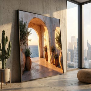 May include: A large square framed wall art piece depicting a Mediterranean stone archway overlooking the sea at sunset. The scene features terracotta pots with green plants and flowers lining the walkway, bathed in warm golden light and shadows.