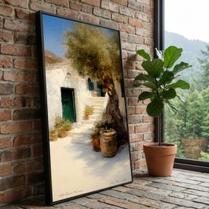 Könnte beinhalten: Gerahmter Kunstdruck, der eine sonnige mediterrane Szene zeigt. Ein weißes Gebäude mit grüner Tür und Fensterläden wird teilweise von einem großen Baum verdeckt. Topfpflanzen säumen einen Weg, der zum Gebäude führt. Das Kunstwerk wird vor einer Backsteinmauer ausgestellt.