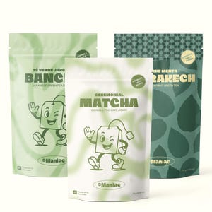 Può includere: Tre confezioni di tè verde del marchio "Maniac". Le confezioni sono etichettate come "Tè Verde Giapponese Bancha", "Matcha Cerimoniale" e "Menta Verde". Ogni confezione presenta un personaggio di bustina di tè dei cartoni animati.