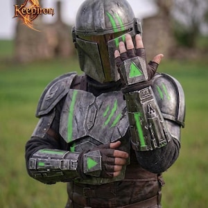 Puede incluir: Una detallada armadura mandaloriana gris met&aacute;lico con detalles en verde. El casco, la placa del pecho y los guanteletes presentan dise&ntilde;os intrincados y texturas desgastadas por la batalla. La armadura incluye un casco, hombreras y guantes. La imagen tambi&eacute;n incluye el texto "Keepiron".