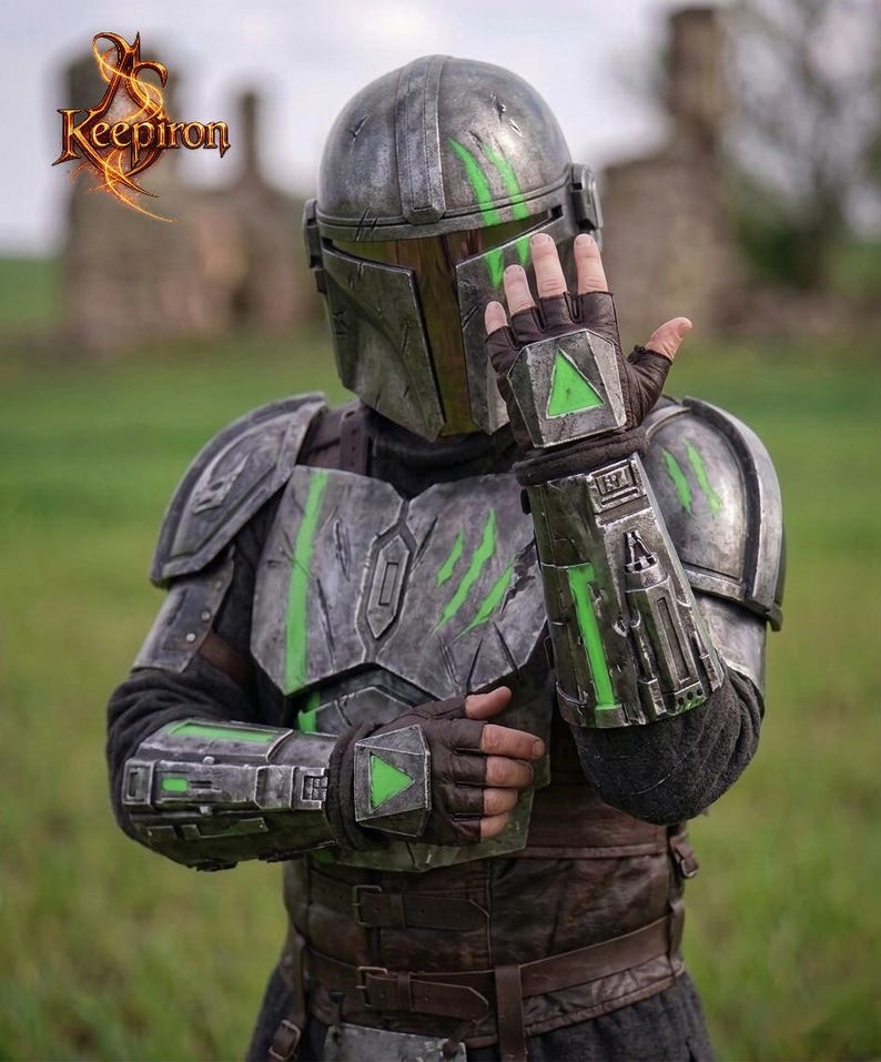 Puede incluir: Una detallada armadura mandaloriana gris met&aacute;lico con detalles en verde. El casco, la placa del pecho y los guanteletes presentan dise&ntilde;os intrincados y texturas desgastadas por la batalla. La armadura incluye un casco, hombreras y guantes. La imagen tambi&eacute;n incluye el texto "Keepiron".