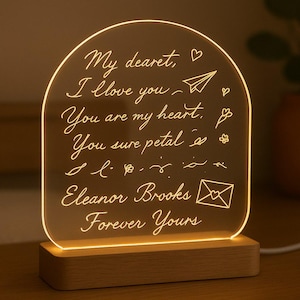 Könnte beinhalten: Leuchtende Acryl-LED-Lampe mit Holzsockel. Sie zeigt den handgeschriebenen Text "My dearest, I love you, You are my heart, You sure petal, Eleanor Brooks, Forever Yours" mit dekorativen Symbolen.