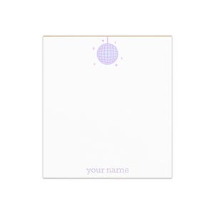 May include: A white notepad with a light purple disco ball illustration at the top. The words "your name" are printed in a light gray font at the bottom of the notepad.