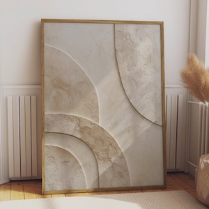 Puede incluir: Una pieza de arte mural rectangular enmarcada en madera clara, con una superficie texturizada de color blanco roto y formas geométricas semicirculares en relieve. La composición muestra formas curvas superpuestas con un acabado rugoso similar al yeso en tonos neutros beige y crema, creando una apariencia táctil y tridimensional.