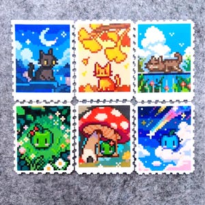 Puede incluir: Seis sellos de arte pixelado con diferentes escenas. Un gato negro bajo una luna creciente, un gato naranja bajo hojas de oto&ntilde;o y un gato marr&oacute;n en una valla. Los sellos restantes representan una rana verde, una rana bajo una seta y una criatura azul.