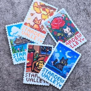 Puede incluir: Una colecci&oacute;n de cinco pegatinas estilo pixel art con escenas de Stardew Valley. Cada pegatina tiene un borde azul claro y representa una escena diferente con un gato, incluyendo un gato en hojas de oto&ntilde;o y un gato bajo un cielo nocturno.