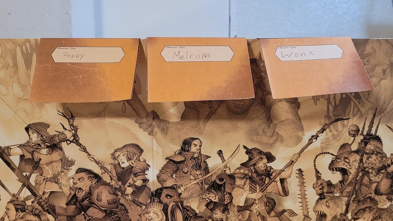 May include: Three tan name tags labelled "Poppy", "Melrum", and "Wonk" are placed above a fantasy illustration. The illustration depicts a battle scene with various characters, weapons, and creatures.